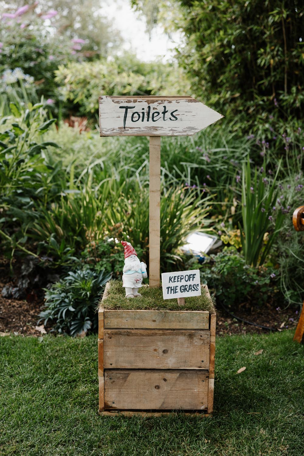 Wooden boxes with gnome, Keep Off The Grass sign, and toilet direction sign.