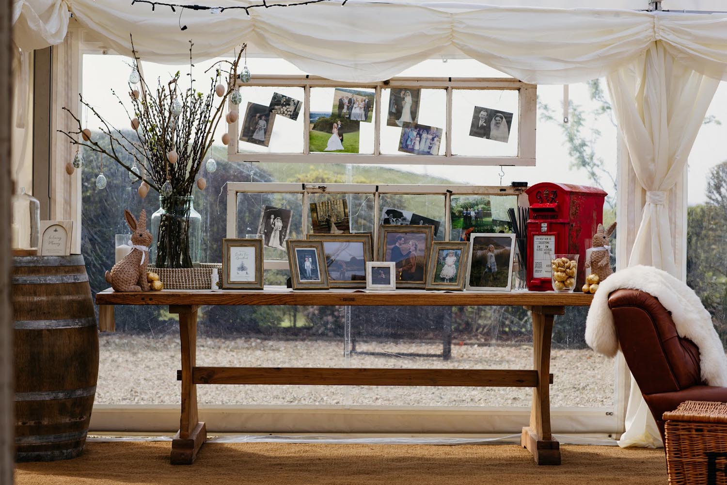 Two window panes display a gallery of photos, branches, and a red mailbox in a decorated tent.